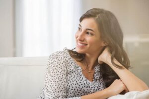 Confident woman relaxing on couch at home. Thoughtful smiling wo