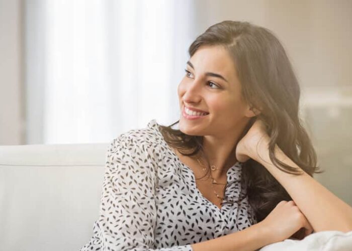 Confident woman relaxing on couch at home. Thoughtful smiling wo